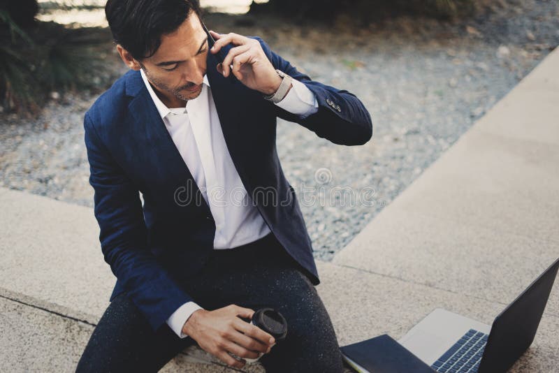 Homem de negócios que usa o smartphone contemporâneo que toma o resto fora do escritório durante o dia do trabalho Guardando as m foto de stock royalty free Homem de negócios que usa o smartphone contemporâneo que toma o resto fora do escritório durante o dia do trabalho Guardando as m foto de stock royalty free