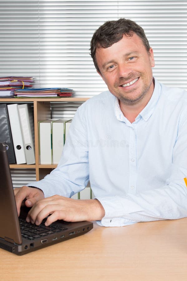 Homem de negócios que usa seu computador em seu escritório imagens de stock royalty free Homem de negócios que usa seu computador em seu escritório imagens de stock royalty free