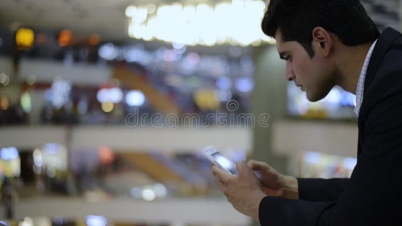 Homem de negócios que usa um telefone celular no shopping