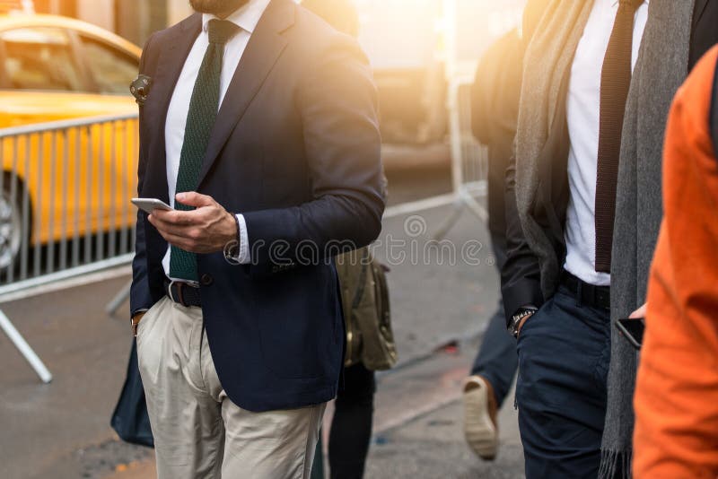 Homem de negócios que veste o terno preto e que usa o smartphone moderno durante a caminhada ao escritório na rua da cidade fotografia de stock Homem de negócios que veste o terno preto e que usa o smartphone moderno durante a caminhada ao escritório na rua da cidade fotografia de stock
