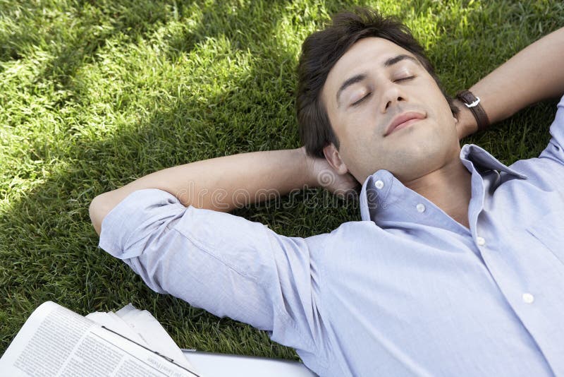 Homem de negócios relaxado Lying On Grass no parque