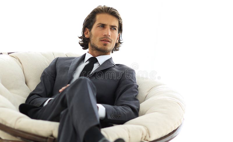 Homem de negócios seguro que senta-se em uma grande cadeira confortável imagens de stock royalty free Homem de negócios seguro que senta-se em uma grande cadeira confortável imagens de stock royalty free