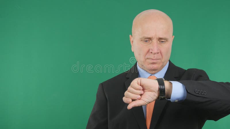 Homem de negócios sério Image Checking Time em seu relógio da mão imagem de stock Homem de negócios sério Image Checking Time em seu relógio da mão imagem de stock