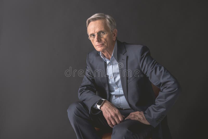 Homem de negócios velho concentrado que localiza no assento foto de stock Homem de negócios velho concentrado que localiza no assento foto de stock