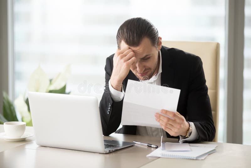 Homem de negócios virado devido à observação do débito de banco imagem de stock Homem de negócios virado devido à observação do débito de banco imagem de stock