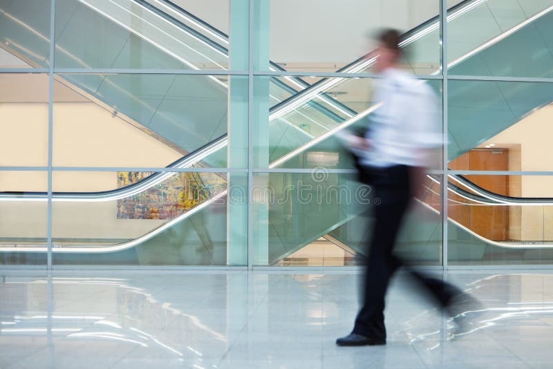 Homem de negócios Walking Quickly para baixo Salão no prédio de escritórios imagem de stock royalty free Homem de negócios Walking Quickly para baixo Salão no prédio de escritórios imagem de stock royalty free