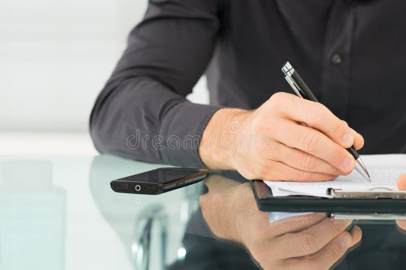 Homem de negócios Writing um documento fotos de stock royalty free Homem de negócios Writing um documento fotos de stock royalty free