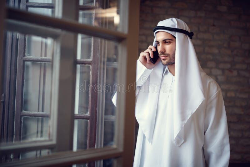 Homem de negócios árabe que fala no telefone celular na empresa imagens de stock Homem de negócios árabe que fala no telefone celular na empresa imagens de stock