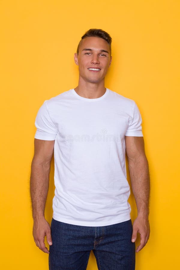 Homem de sorriso considerável novo no t-shirt branco fotografia de stock Homem de sorriso considerável novo no t-shirt branco fotografia de stock