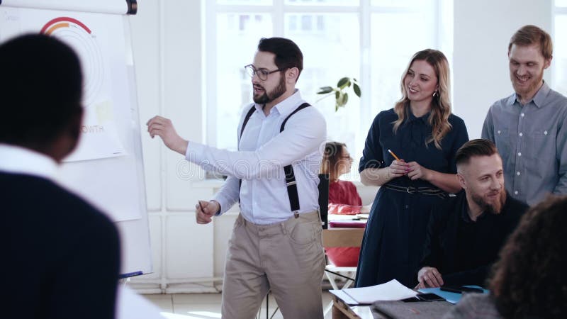 Homem de sorriso novo ativo feliz do treinador da finança que conduz a discussão ativa com a equipe diversa na reunião da conferê vídeos de arquivo Homem de sorriso novo ativo feliz do treinador da finança que conduz a discussão ativa com a equipe diversa na reunião da conferê vídeos de arquivo