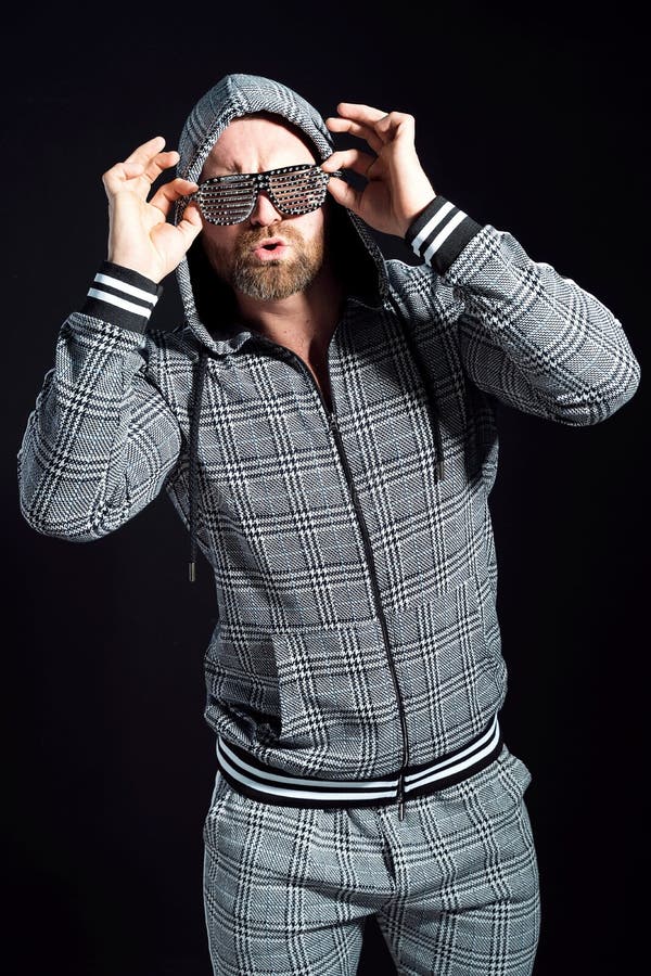Homem de terno cinza com capuz em óculos de discoteca contra fundo escuro no estúdio fotos de stock Homem de terno cinza com capuz em óculos de discoteca contra fundo escuro no estúdio fotos de stock