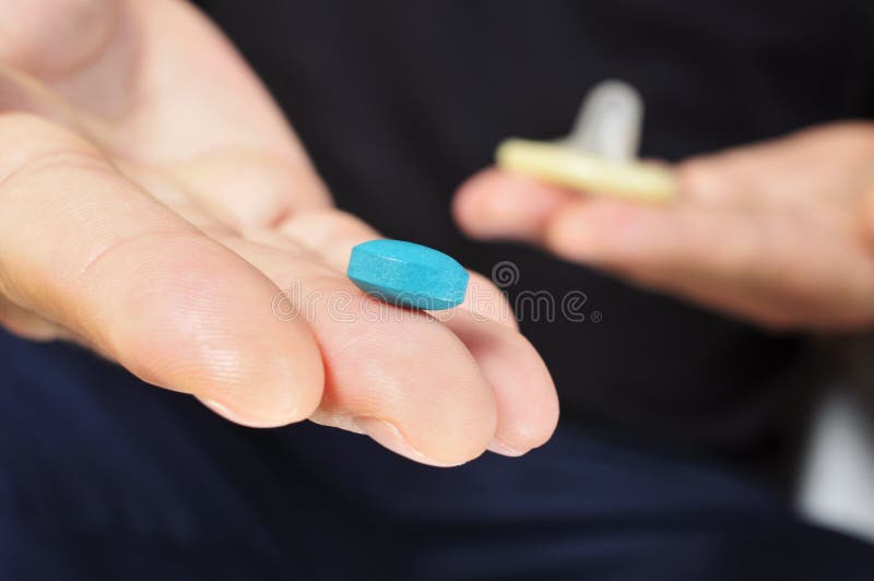 Homem de Yougn com comprimido e o preservativo azuis