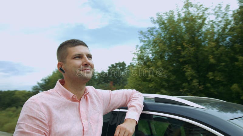 Homem deleitado alegre que inclina-se em seu carro fora