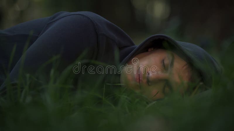 Homem desabrigado que dorme na grama no parque, na pobreza e no conceito social das edições fotos de stock royalty free Homem desabrigado que dorme na grama no parque, na pobreza e no conceito social das edições fotos de stock royalty free