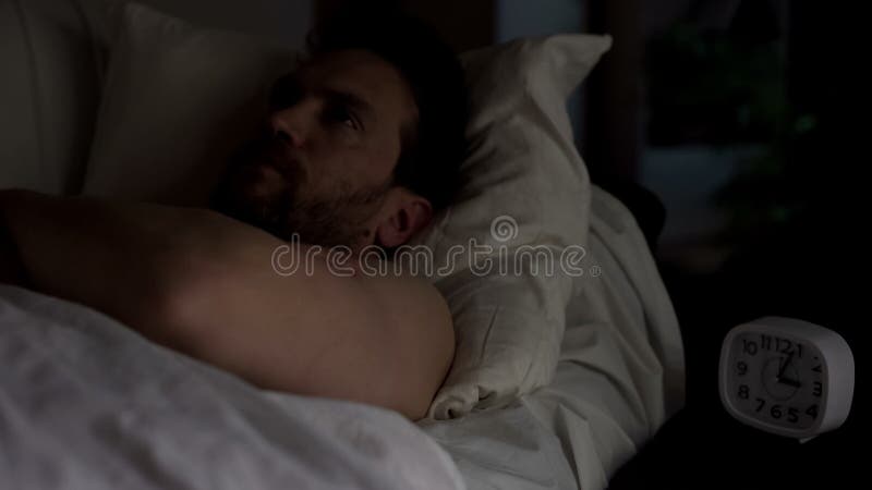 Homem desagradado que encontra-se na cama incapaz de cair adormecido, olhando o teto, insônia fotos de stock Homem desagradado que encontra-se na cama incapaz de cair adormecido, olhando o teto, insônia fotos de stock