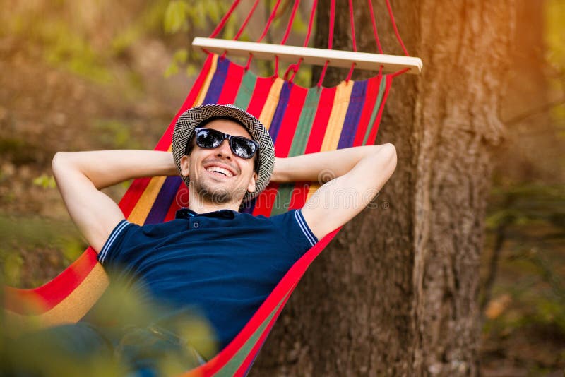 Homem despreocupado e livre que aumenta seus braços cercados do resto do quando da natureza da floresta na rede foto de stock Homem despreocupado e livre que aumenta seus braços cercados do resto do quando da natureza da floresta na rede foto de stock