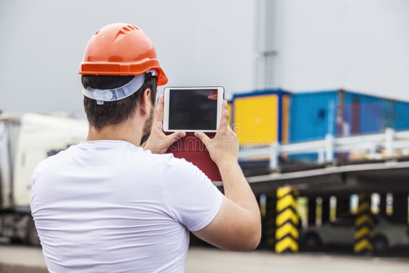 Homem do construtor que trabalha com uma tabuleta em um capacete protetor fotos de stock Homem do construtor que trabalha com uma tabuleta em um capacete protetor fotos de stock