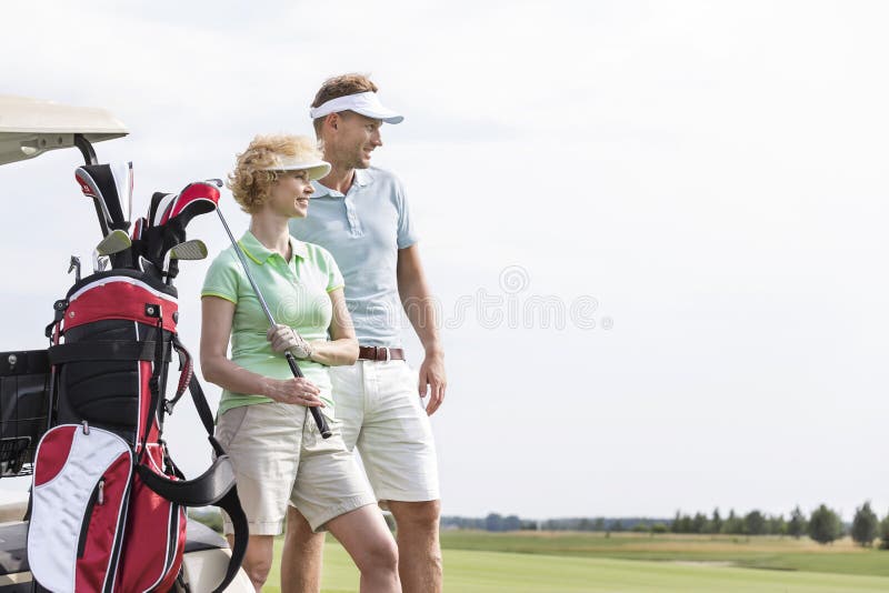 Smiling men and women standing at golf course against clear sky. Smiling men and women standing at golf course against clear sky