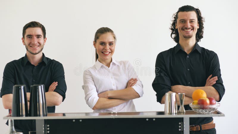 Homem e mulher do barman de Professinal que sorriem na tabela móvel da barra no estúdio branco do fundo imagens de stock Homem e mulher do barman de Professinal que sorriem na tabela móvel da barra no estúdio branco do fundo imagens de stock