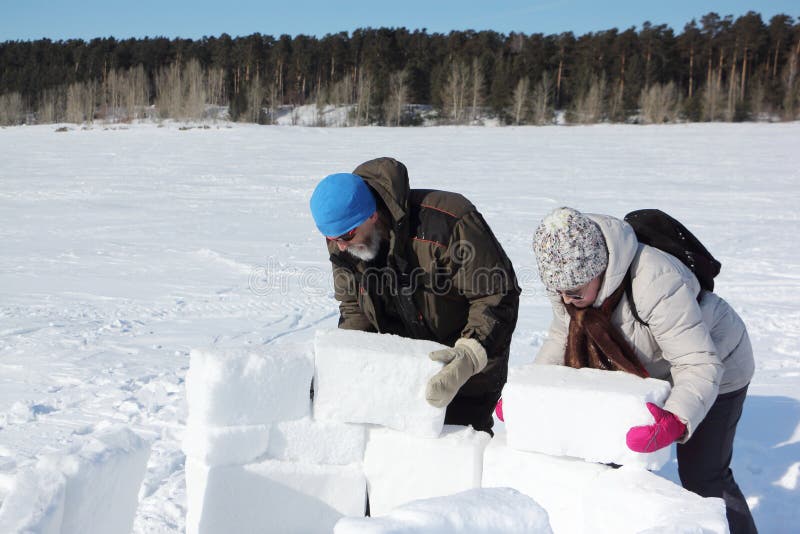 Homem e mulher que constroem um iglu na clareira nevado, Novosibirsk, Rússia imagem de stock Homem e mulher que constroem um iglu na clareira nevado, Novosibirsk, Rússia imagem de stock