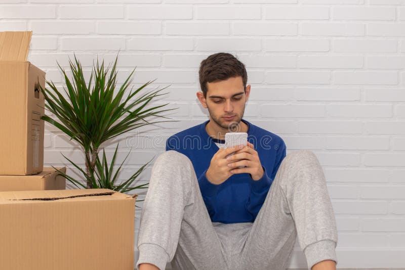 Homem em apartamento com caixas móveis e telefone celular imagens de stock