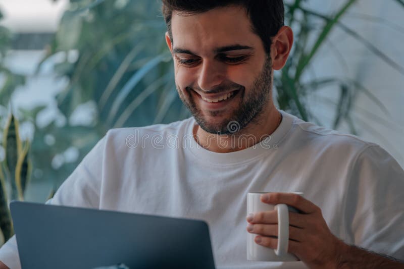 Homem em casa com computador e xícara de café imagens de stock