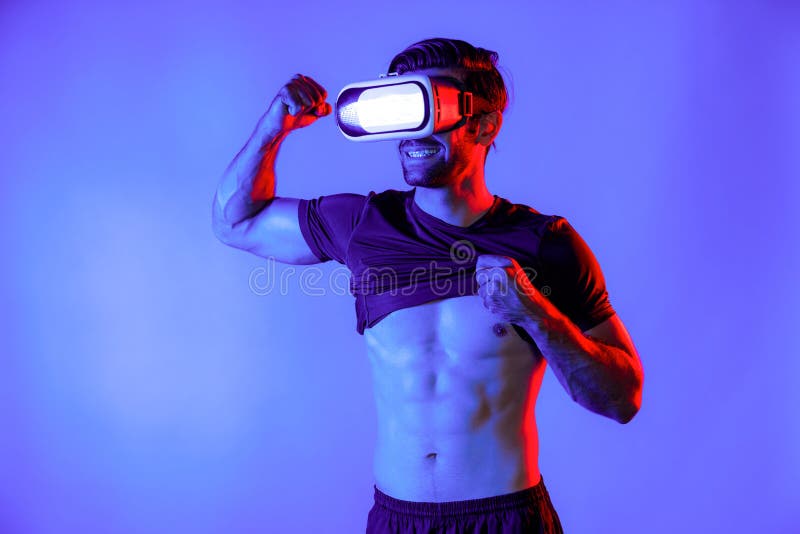 Happy man with VR goggle flexing muscle at neon light background. Healthy person with casual cloth relaxing and exercising by using virtual reality simulator technology. Represent healthy. Deviation. Happy man with VR goggle flexing muscle at neon light background. Healthy person with casual cloth relaxing and exercising by using virtual reality simulator technology. Represent healthy. Deviation.
