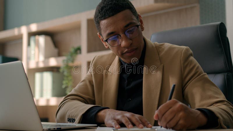 Homem-empresário africano, homem empresário, empresário, analista de contabilidade escreve anotações lidas informações sobre lapto fotos de stock royalty free