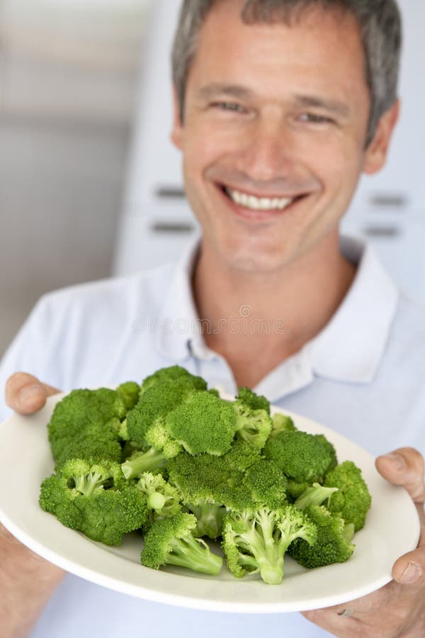 Homem envelhecido médio que prende uma placa dos bróculos imagens de stock royalty free Homem envelhecido médio que prende uma placa dos bróculos imagens de stock royalty free
