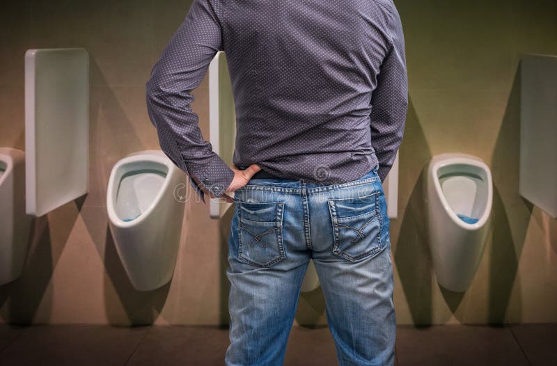 Homem ereto que faz xixi a um mictório no toalete imagem de stock Homem ereto que faz xixi a um mictório no toalete imagem de stock
