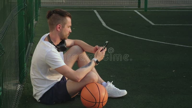 Um Homem Relaxando Depois Do Treino De Basquetebol E Pesquisando