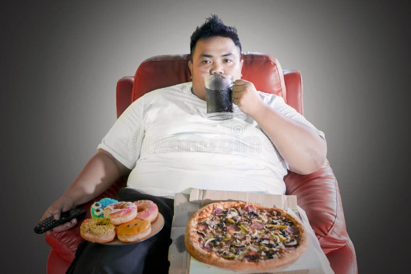 Homem excesso de peso com alimentos de sucata durante a tevê do relógio