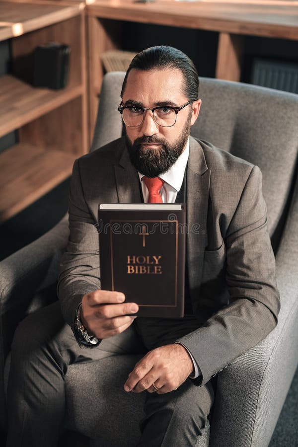 Homem farpado de cabelo escuro que guarda a Bíblia Sagrada fotos de stock Homem farpado de cabelo escuro que guarda a Bíblia Sagrada fotos de stock