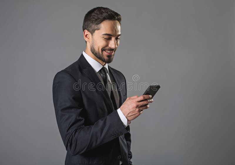 Homem farpado de sorriso alegre que usa o smartphone foto de stock royalty free Homem farpado de sorriso alegre que usa o smartphone foto de stock royalty free