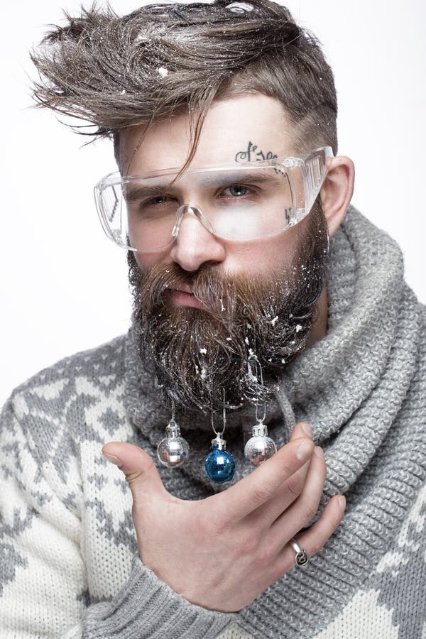 Homem farpado engraçado em uma imagem do ` s do ano novo com neve e decorações em sua barba Festa do Natal imagem de stock royalty free Homem farpado engraçado em uma imagem do ` s do ano novo com neve e decorações em sua barba Festa do Natal imagem de stock royalty free