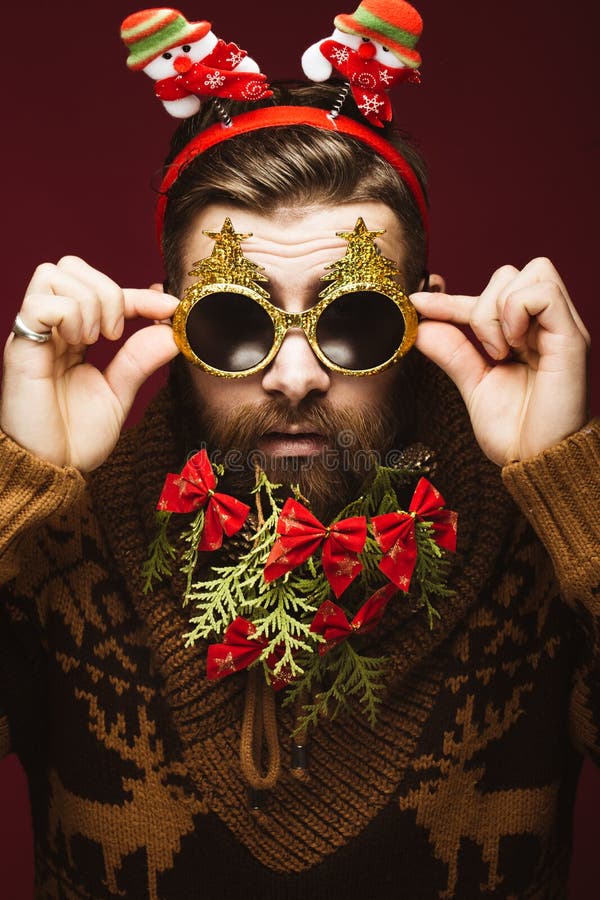 Homem farpado engraçado em uma imagem do ` s do ano novo como Santa Claus com as decorações em sua barba Festa do Natal foto de stock royalty free Homem farpado engraçado em uma imagem do ` s do ano novo como Santa Claus com as decorações em sua barba Festa do Natal foto de stock royalty free