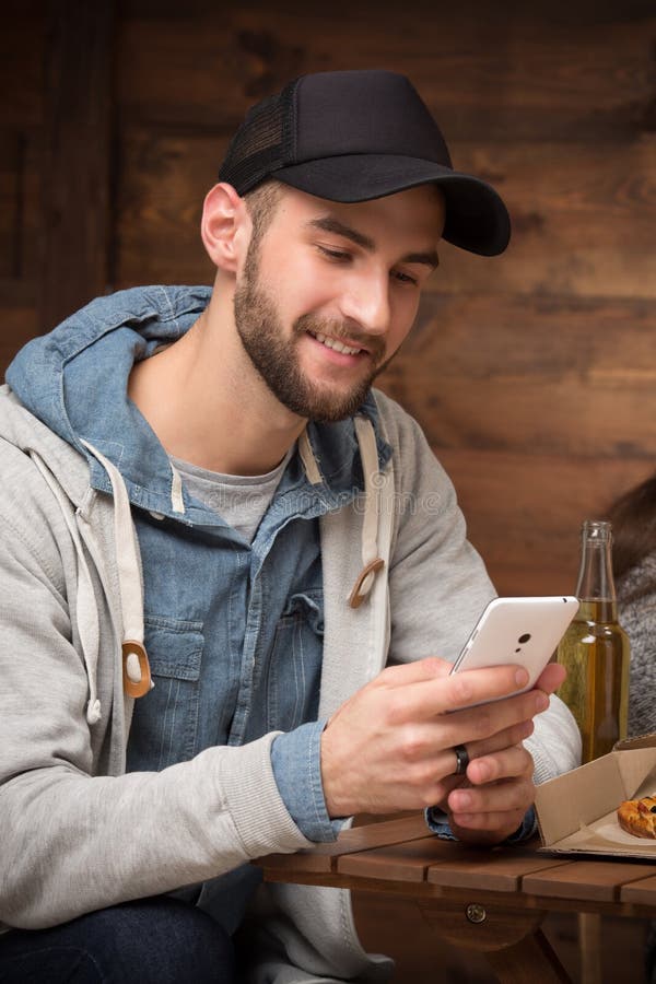 Homem feliz do moderno que senta-se no café com telefone celular imagem de stock Homem feliz do moderno que senta-se no café com telefone celular imagem de stock