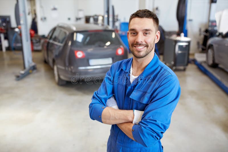 Car service, repair, maintenance and people concept - happy smiling auto mechanic man or smith at workshop. Car service, repair, maintenance and people concept - happy smiling auto mechanic man or smith at workshop