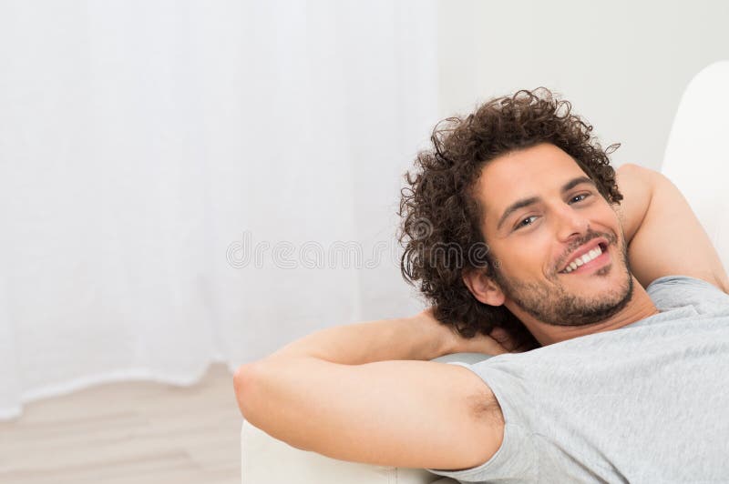 Homem feliz que descansa no sofá