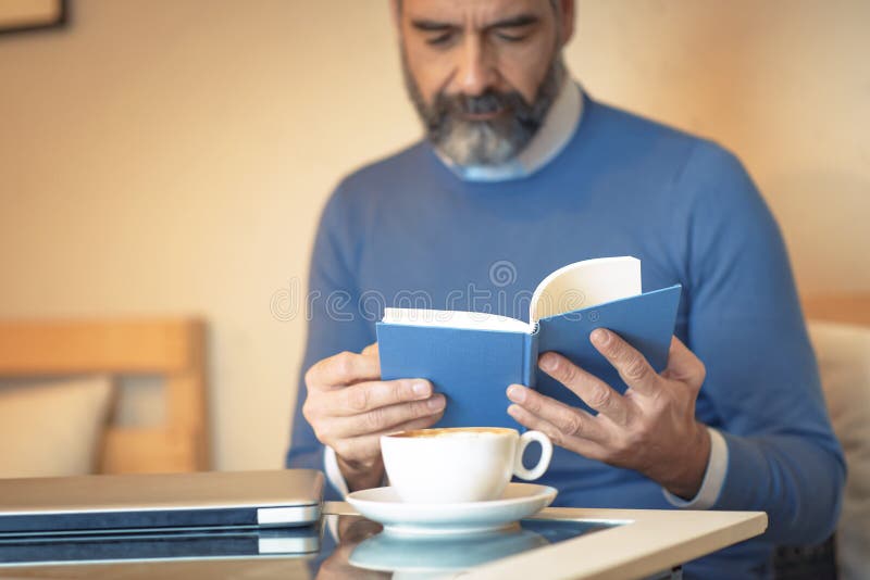 Homem idoso que lê um livro em uma cafetaria imagem de stock royalty free Homem idoso que lê um livro em uma cafetaria imagem de stock royalty free