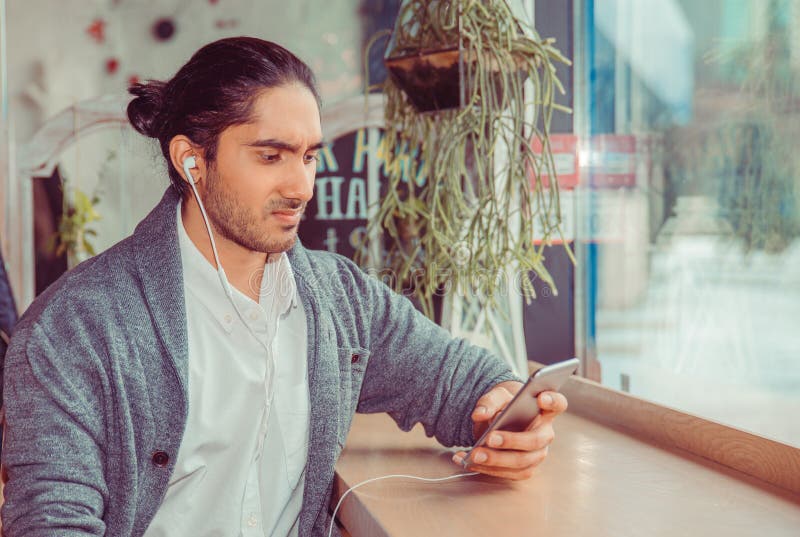 Homem infeliz com os fones de ouvido que olham a um telefone celular fotos de stock Homem infeliz com os fones de ouvido que olham a um telefone celular fotos de stock