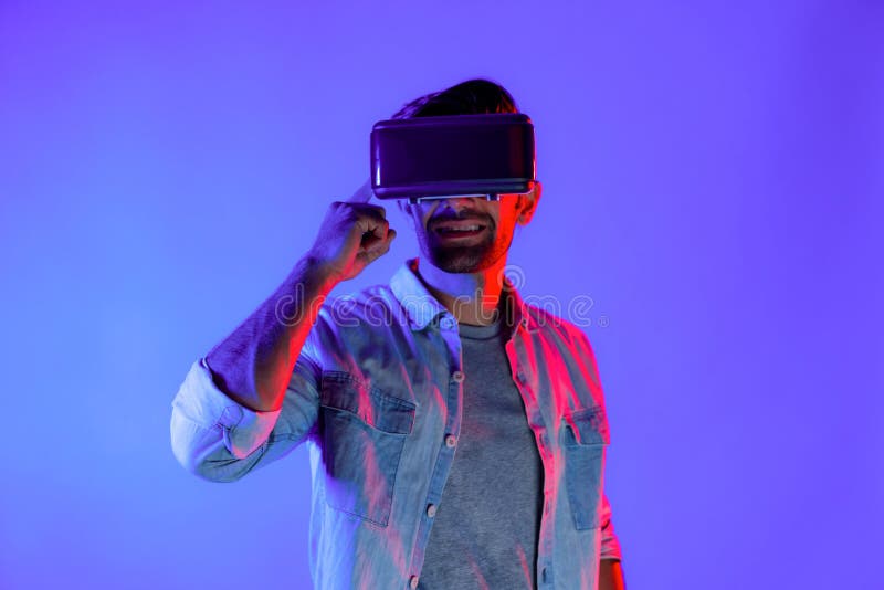 Man wearing virtual reality headset while enter in metaverse. Caucasian man standing at colorful neon light and using futuristic digital technology virtual goggles or VR for playing games. Deviation. Man wearing virtual reality headset while enter in metaverse. Caucasian man standing at colorful neon light and using futuristic digital technology virtual goggles or VR for playing games. Deviation.
