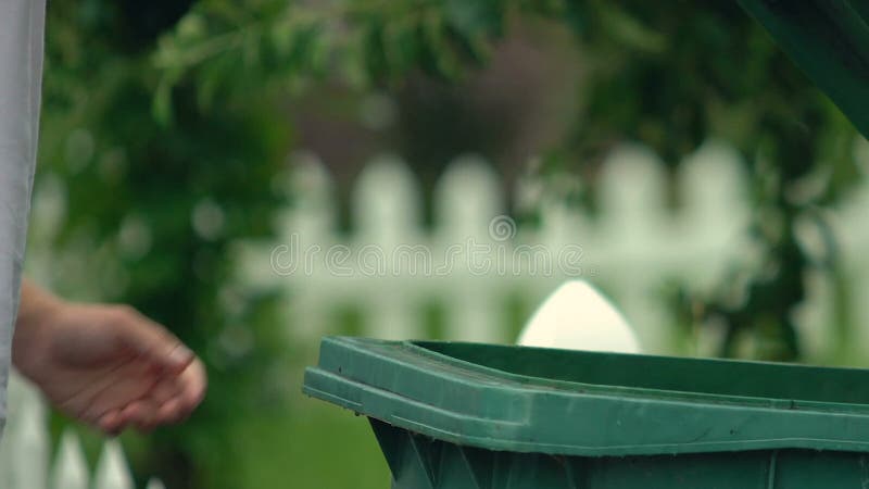 Homem jogando lixo em recipiente de plástico verde, utilização de resíduos, ecologia