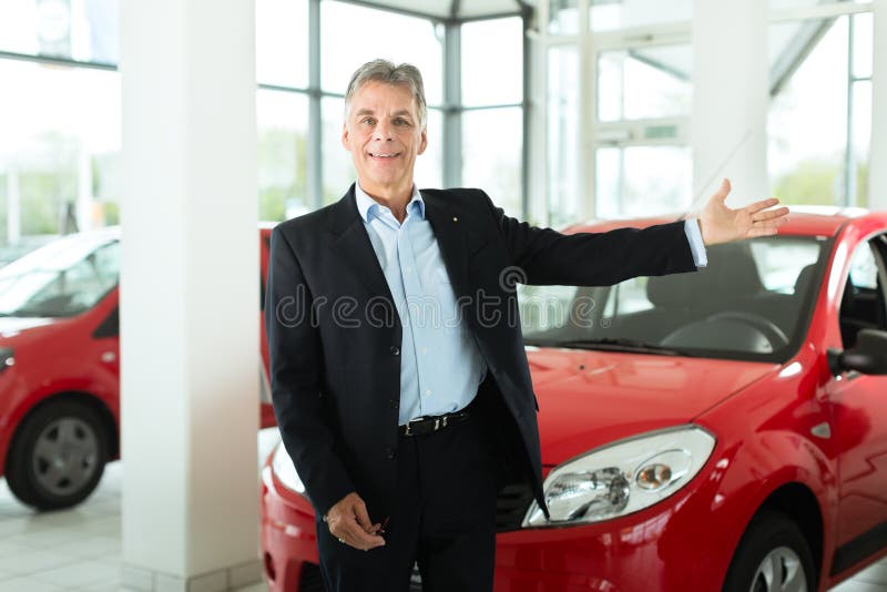 Mature single man with red auto in light car dealership, he is obviously buying a car or is a car dealer. Mature single man with red auto in light car dealership, he is obviously buying a car or is a car dealer