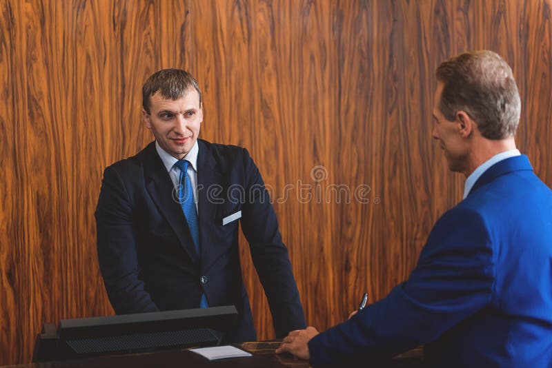 Homem maduro que comunica-se ao recepcionista foto de stock royalty free Homem maduro que comunica-se ao recepcionista foto de stock royalty free