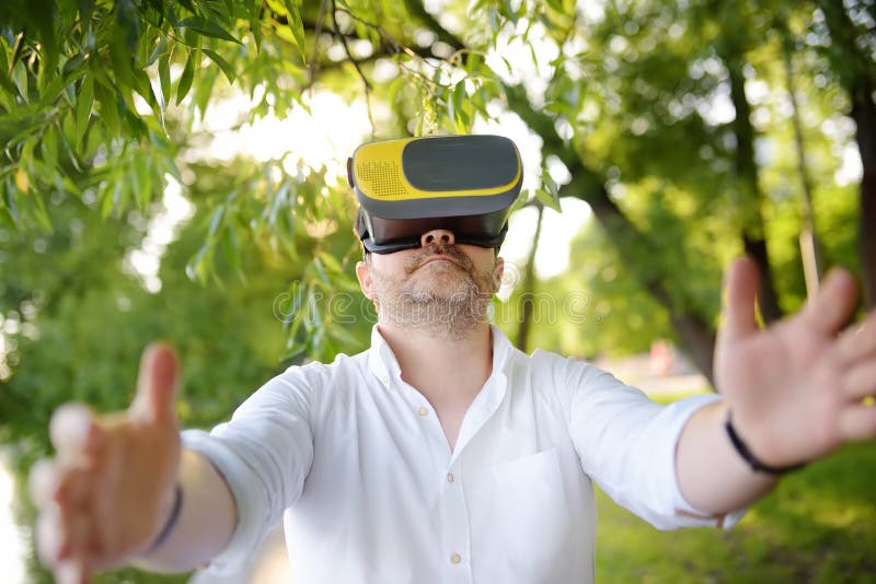 Homem maduro que usa os auriculares da realidade virtual exteriores VR, vidros de VR, experiência aumentada da realidade foto de stock Homem maduro que usa os auriculares da realidade virtual exteriores VR, vidros de VR, experiência aumentada da realidade foto de stock