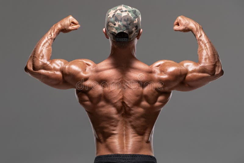 Homem muscular da vista traseira que mostra para tr?s os m?sculos e o b?ceps, isolados no fundo cinzento Torso despido masculino foto de stock royalty free Homem muscular da vista traseira que mostra para tr?s os m?sculos e o b?ceps, isolados no fundo cinzento Torso despido masculino foto de stock royalty free