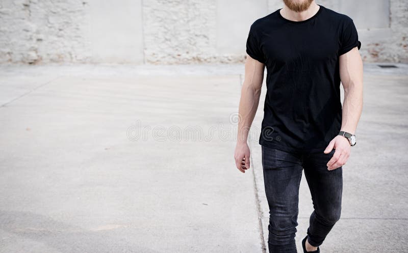 Homem muscular novo que veste o tshirt preto e as calças de brim que andam no distrito urbano Fundo borrado Modelo de Hotizontal imagens de stock royalty free Homem muscular novo que veste o tshirt preto e as calças de brim que andam no distrito urbano Fundo borrado Modelo de Hotizontal imagens de stock royalty free