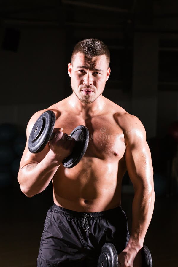 Homem muscular que dá certo no gym que faz exercícios com pesos nos bíceps, Abs despido masculino forte do torso fotos de stock royalty free Homem muscular que dá certo no gym que faz exercícios com pesos nos bíceps, Abs despido masculino forte do torso fotos de stock royalty free