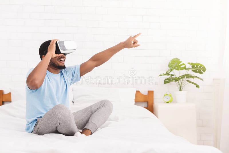 Homem negro novo entusiasmado que usa auriculares da realidade virtual imagens de stock royalty free Homem negro novo entusiasmado que usa auriculares da realidade virtual imagens de stock royalty free